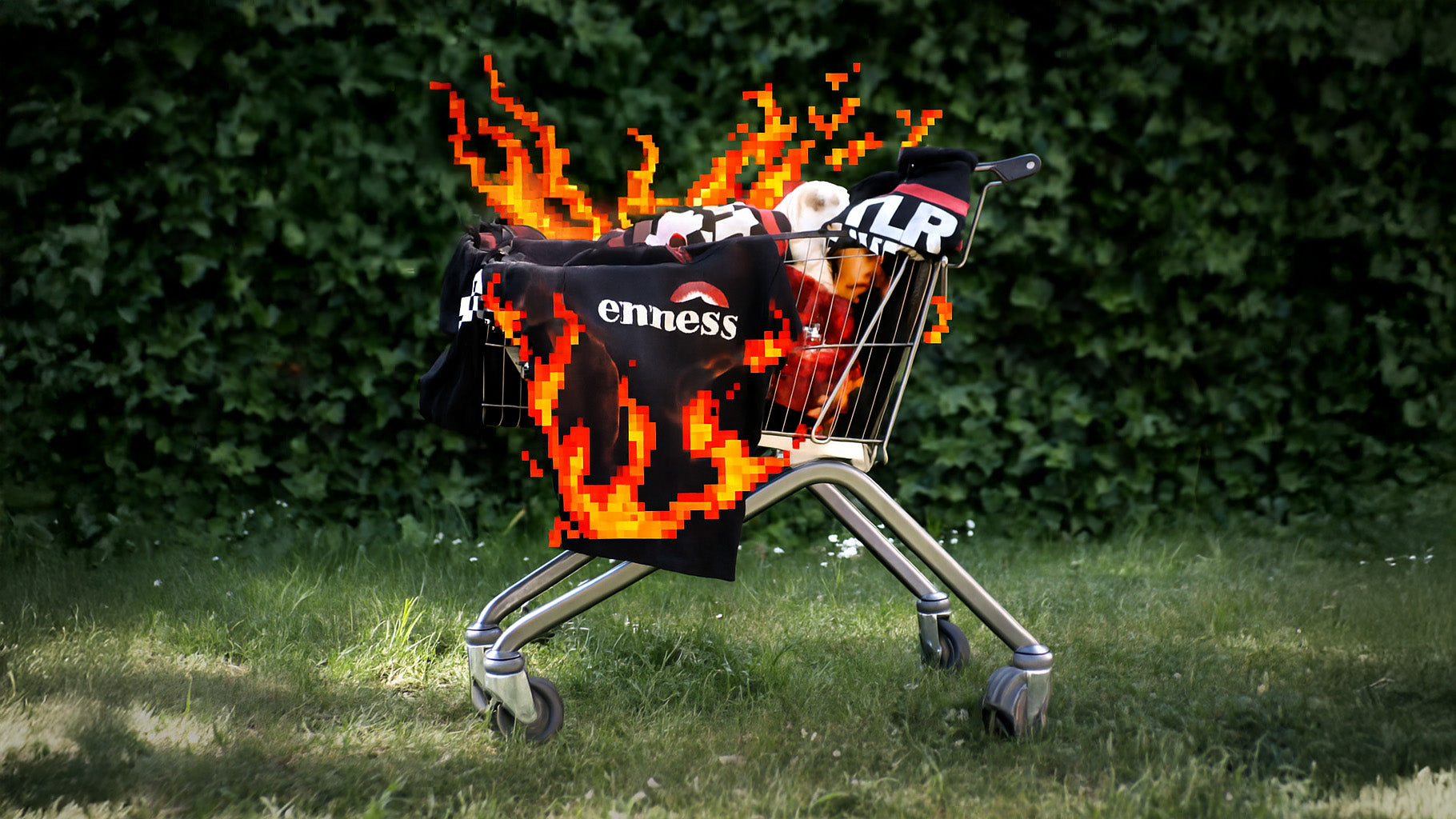 Einkaufswagen mit Nazi-Print T-Shirts steht auf einer Wiese und scheint in pixeligen Flammen zu brennen.
